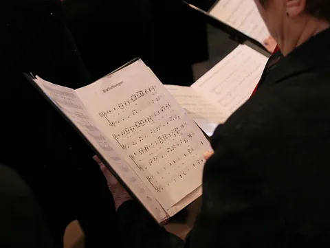 Person hält geöffnetes Notenblatt während einer Aufführung.