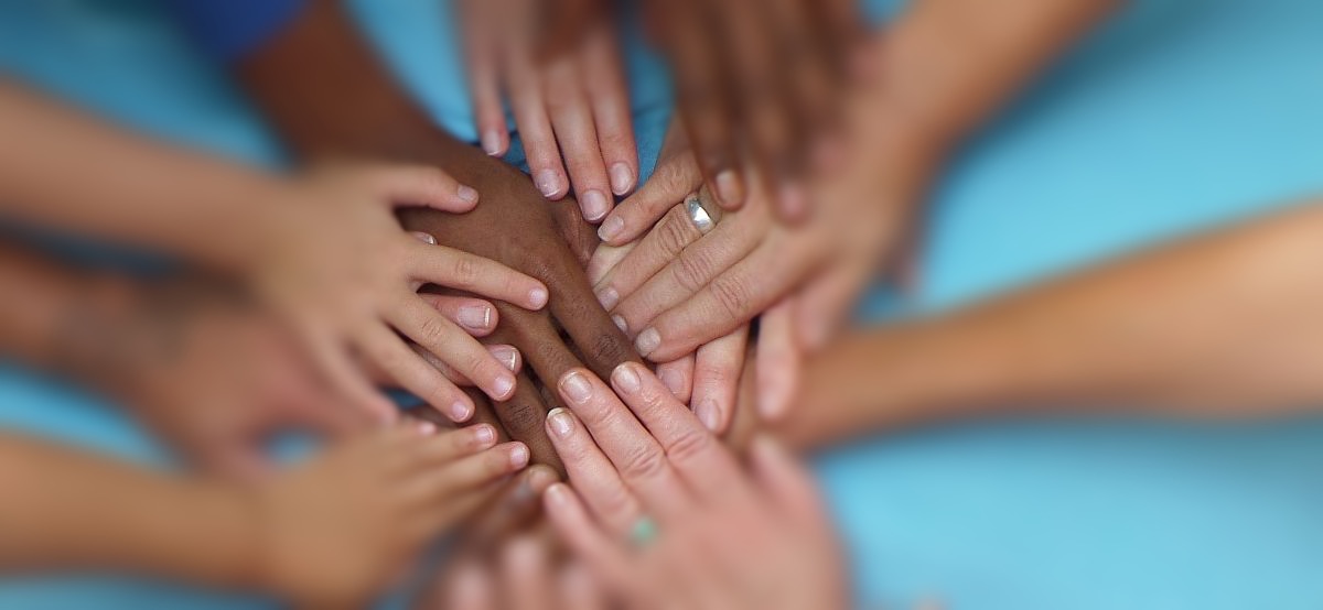 Diverse Hände unterschiedlichen Alters und Hautfarben übereinander gestapelt.