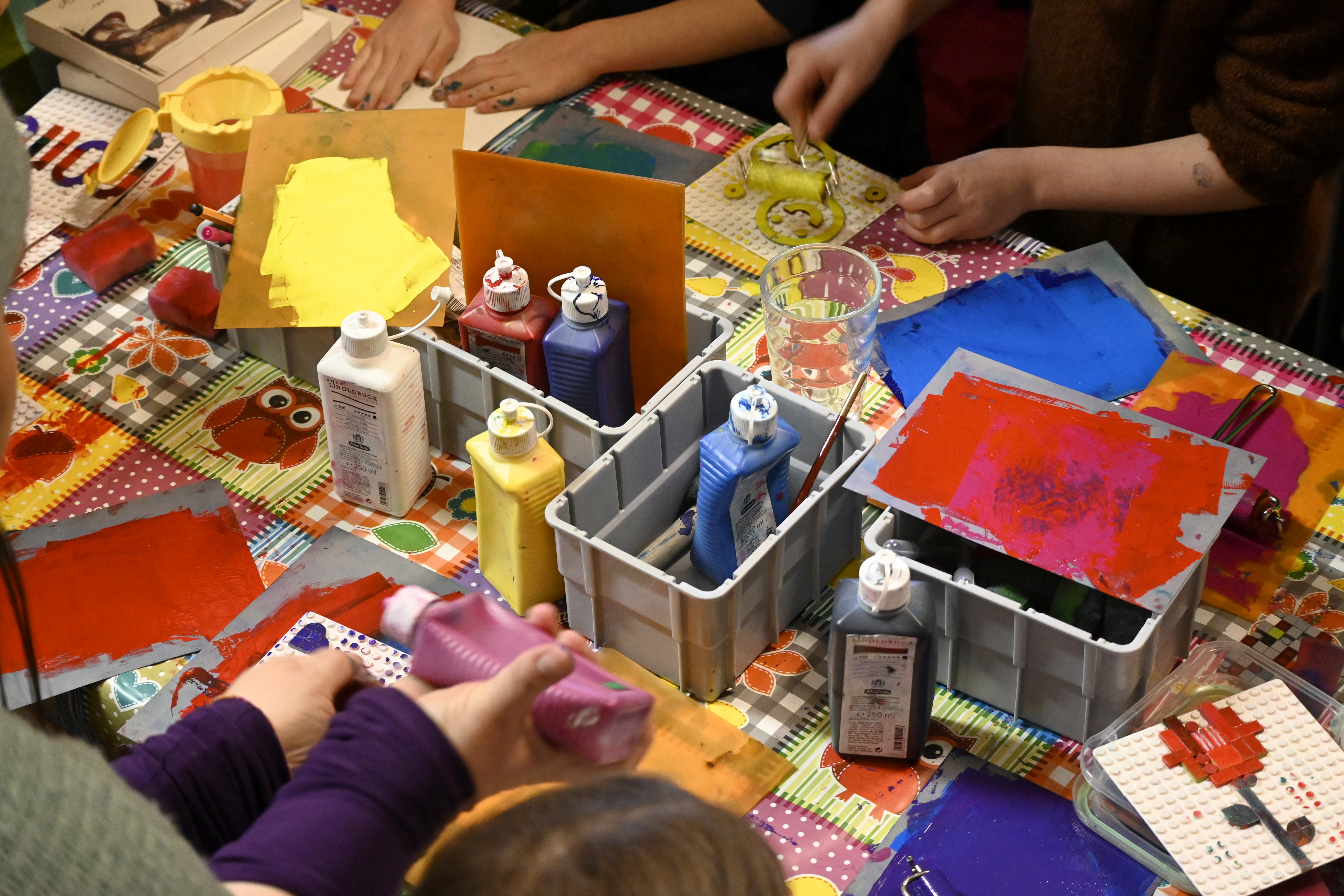Menschen bei Kunstaktivitäten mit Farben und verschiedenen Bastelmaterialien.