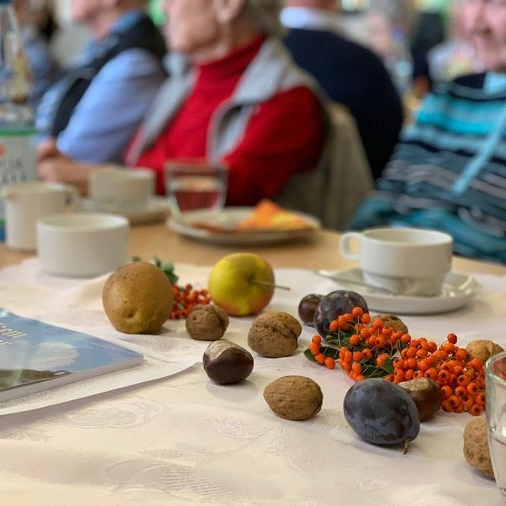 Tisch mit Herbstdekorationen und Menschen im Hintergrund.