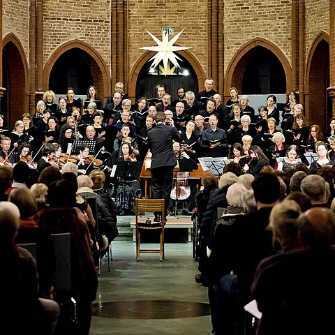 Großer Chor und Orchester treten vor Publikum in Backsteinkirche auf.
